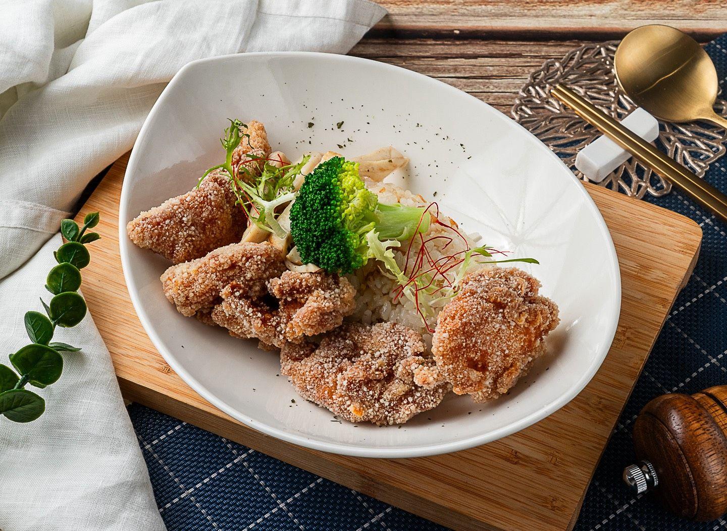 白飯上鋪著酥炸魚塊，旁邊有綠花椰與香草
