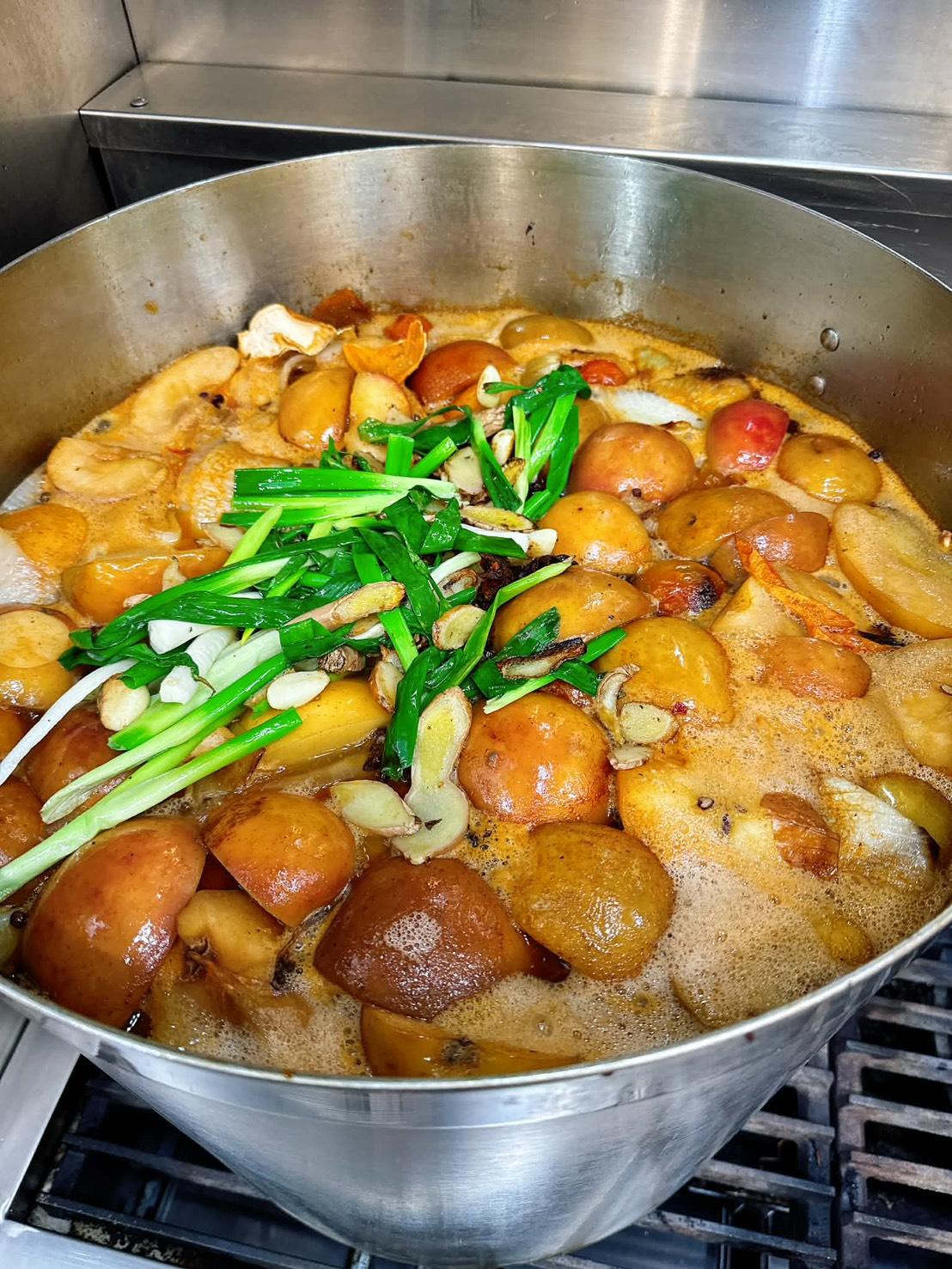 大鍋裡熬著湯底，可見烤過的番茄、洋蔥、蒜頭與青蔥